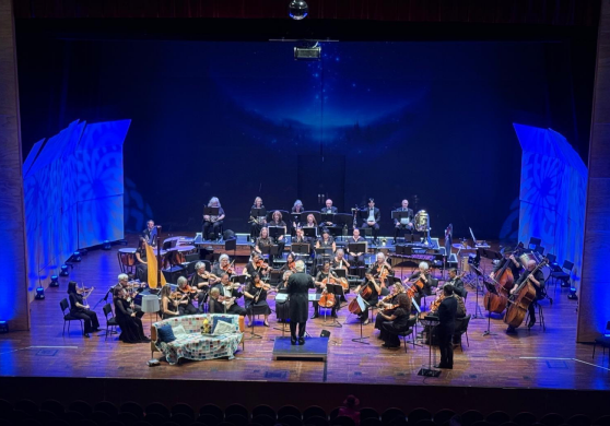 An orchestra performing on a blue-lit stage