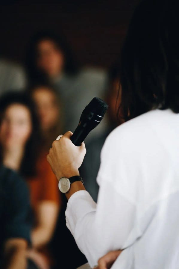 An audience member speaking into a handheld microphone